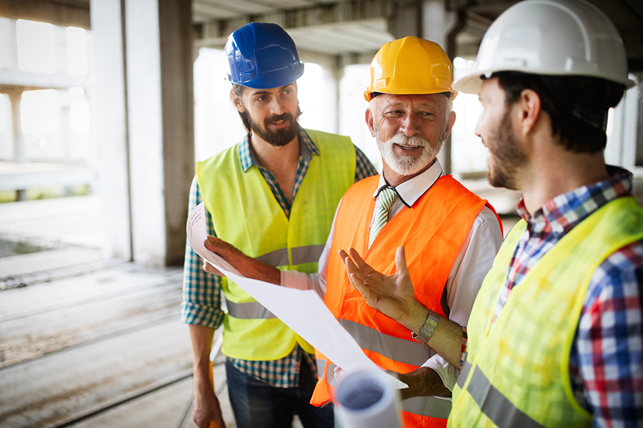 Specialized Business Insurance - Happy Construction Workers Looking Over Plans at a Construction Site