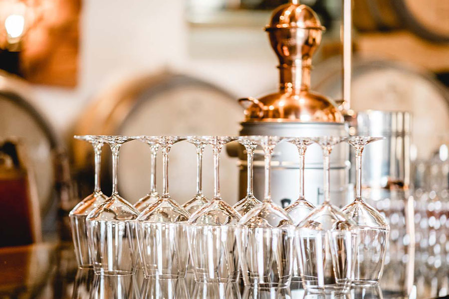 Distillery Insurance - Close-up of an Glassware and an Alembic Still Used for Making Alcohol inside a Distillery with Whisky Barrels in the Background