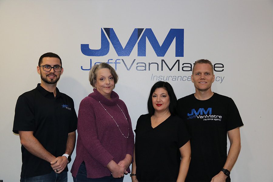 About - Jeff Van Matre Insurance Agency Team Standing and Posing in Front of the Agency Logo